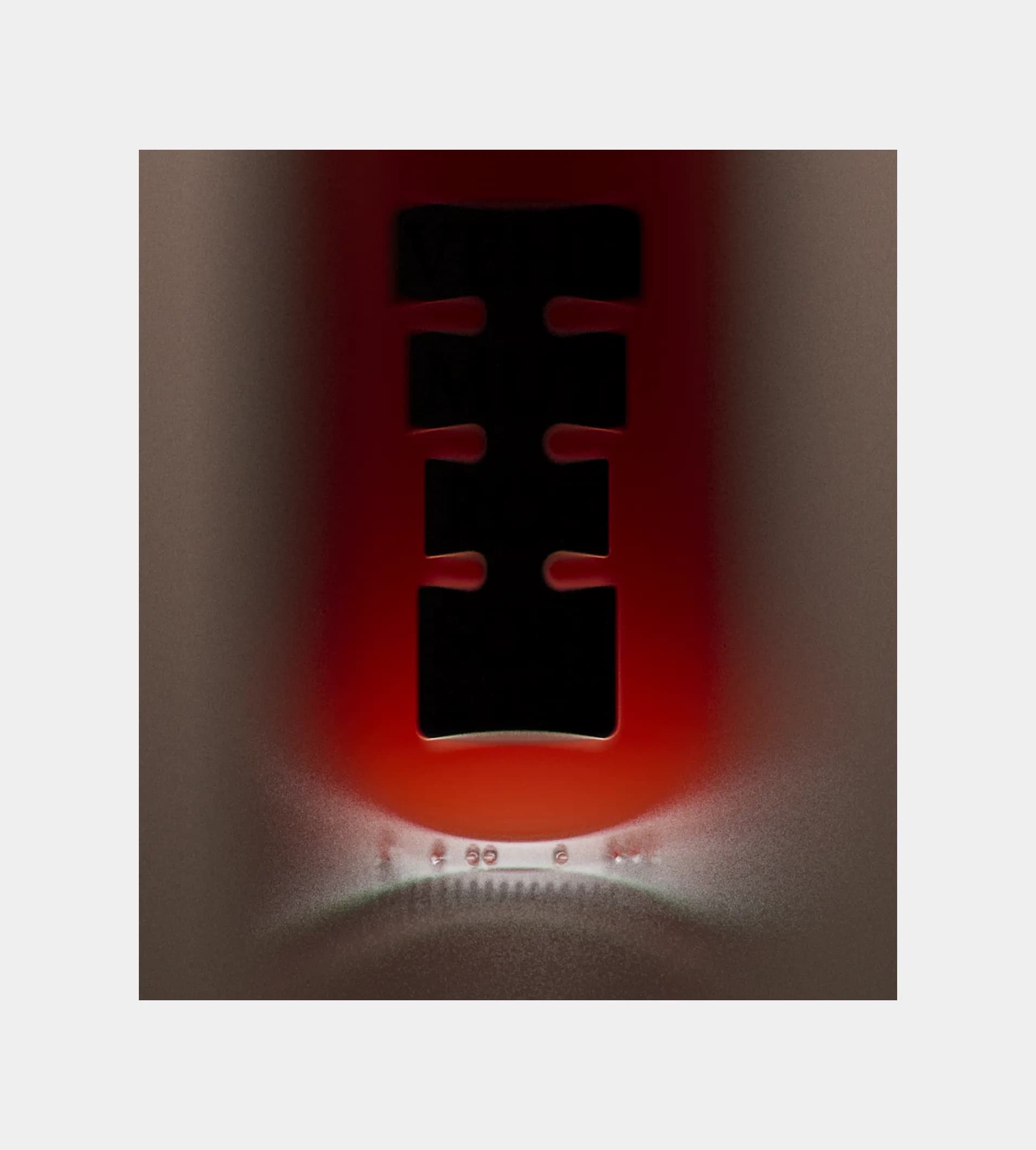Macro close-up of the Shwung label cutout on a dark red bottle, showing the die-cut letter shape backlit by the deep red of the glass.
