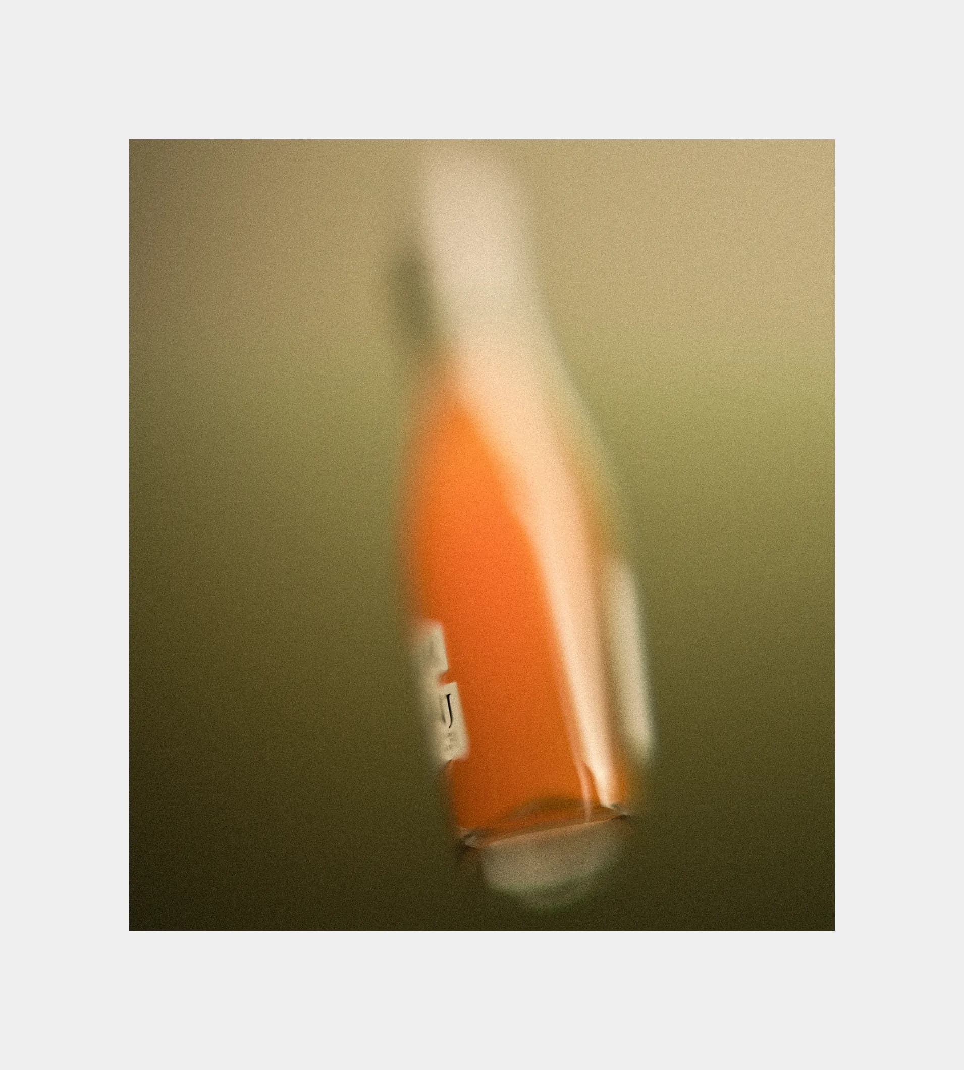 Extreme close-up of an orange Shwung bottle shot against an olive green background, with the label typography partially visible at the bottom edge.