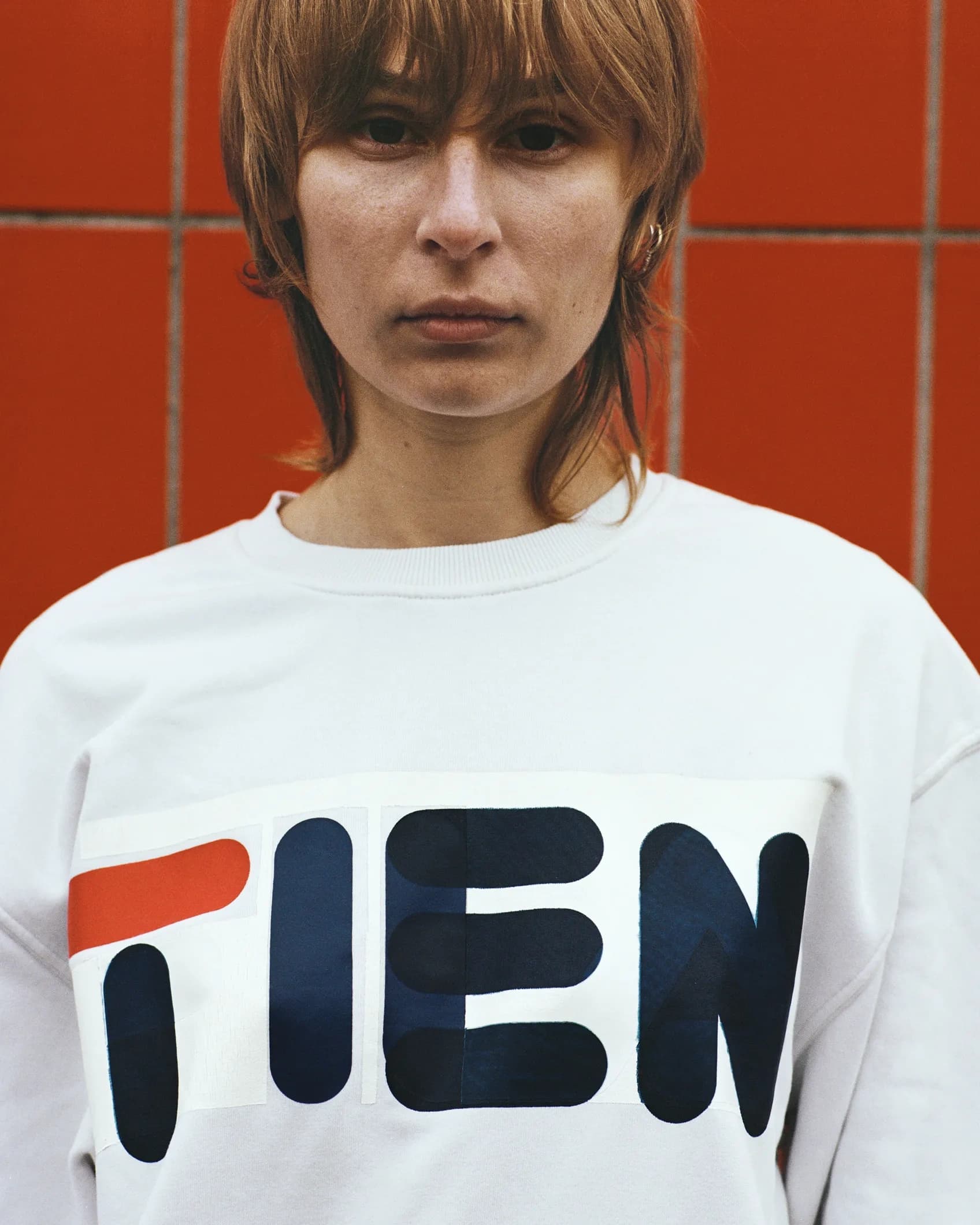Close-up of a person wearing a Fila longsleeve with the letters of the logo changed to TIEN, shot for the TIEN campaign
