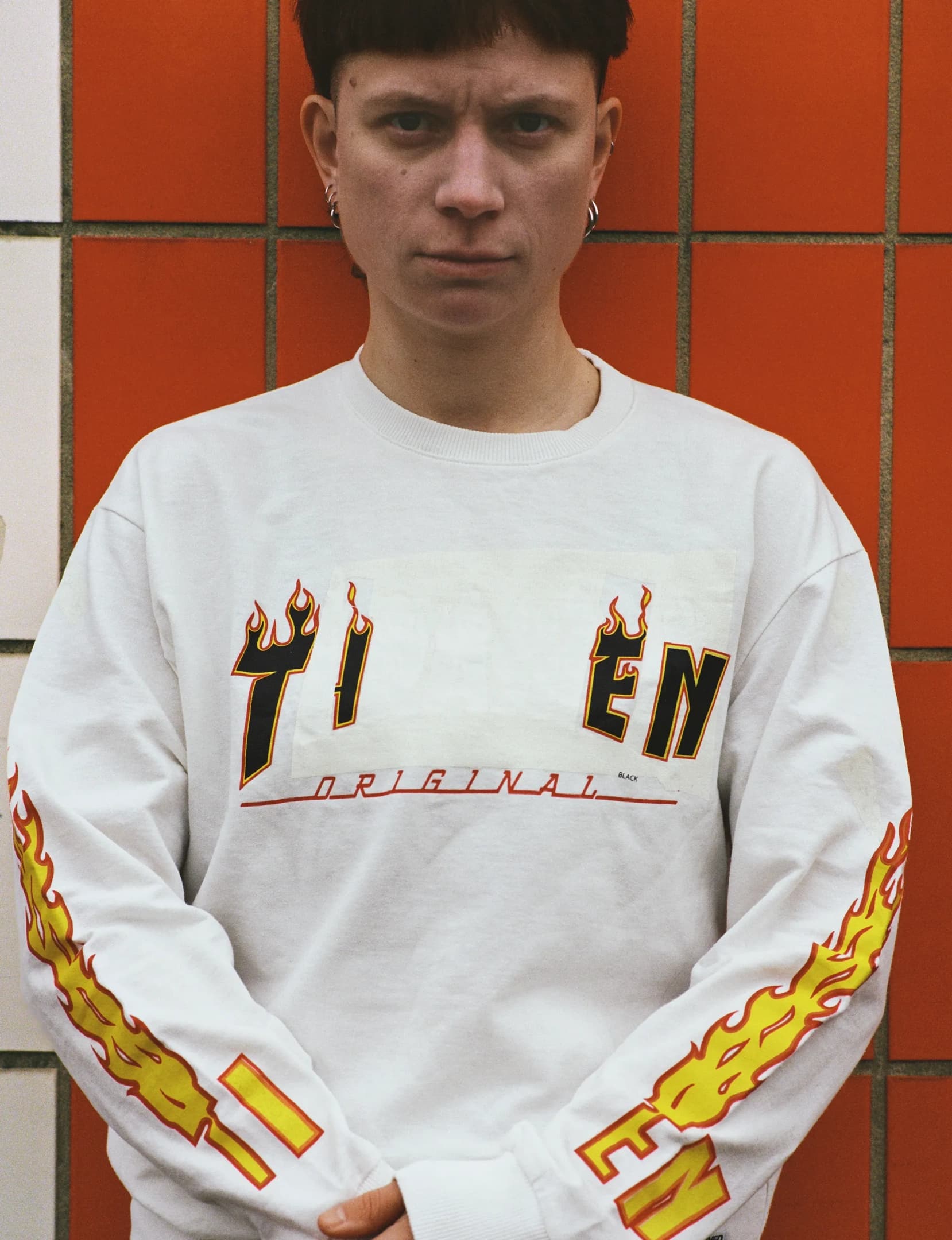 Close-up of a white Thrasher longsleve with logo reworked to read TIEN, keeping the original layout intact.