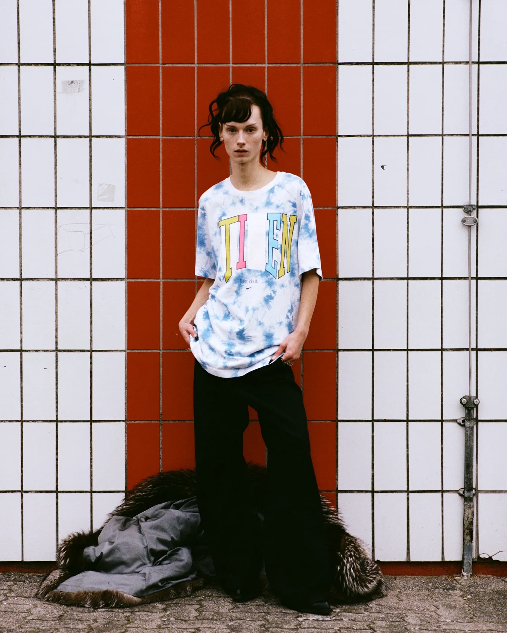 Close-up of a tie-dye Nike t-shirt with a varsity-style TIEN wordmark printed on the chest in yellow, pink and blue, keeping the original Just Do It tagline and swoosh below.