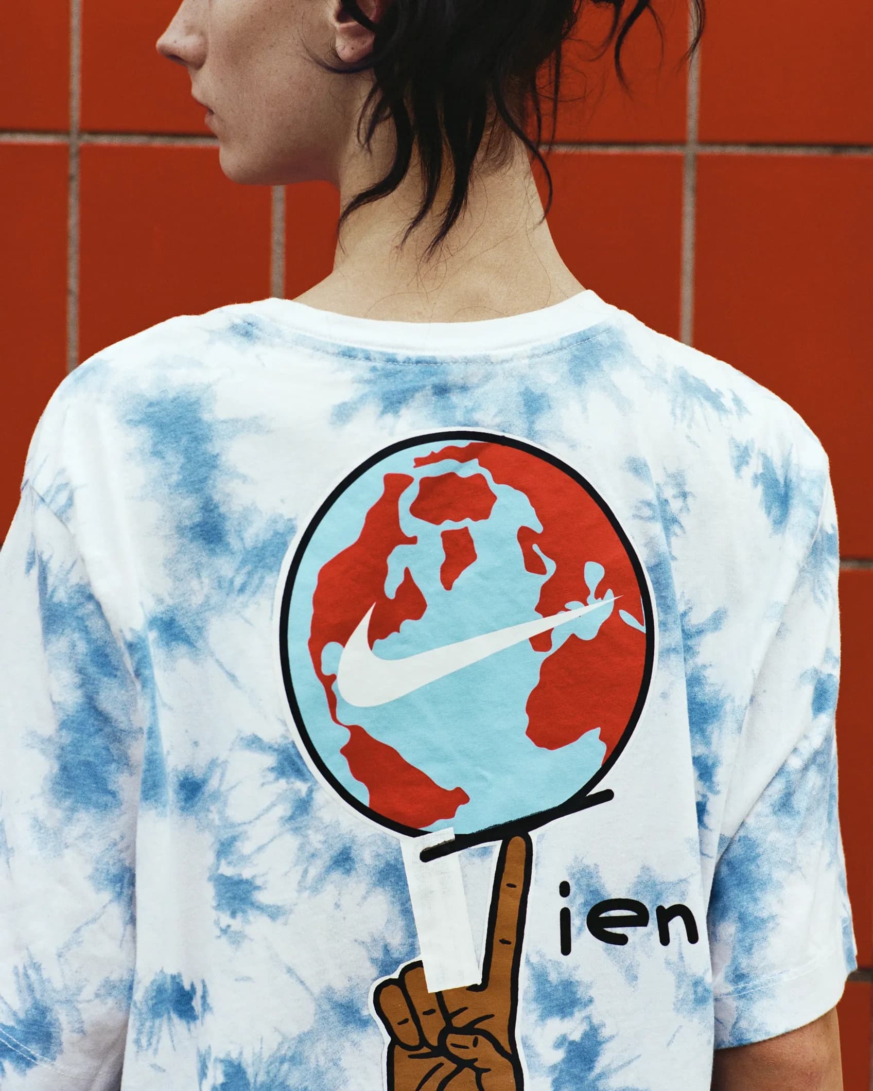 Back of the same tie-dye Nike t-shirt showing a globe graphic with a Nike swoosh, sourced as a vintage piece for the TIEN campaign.