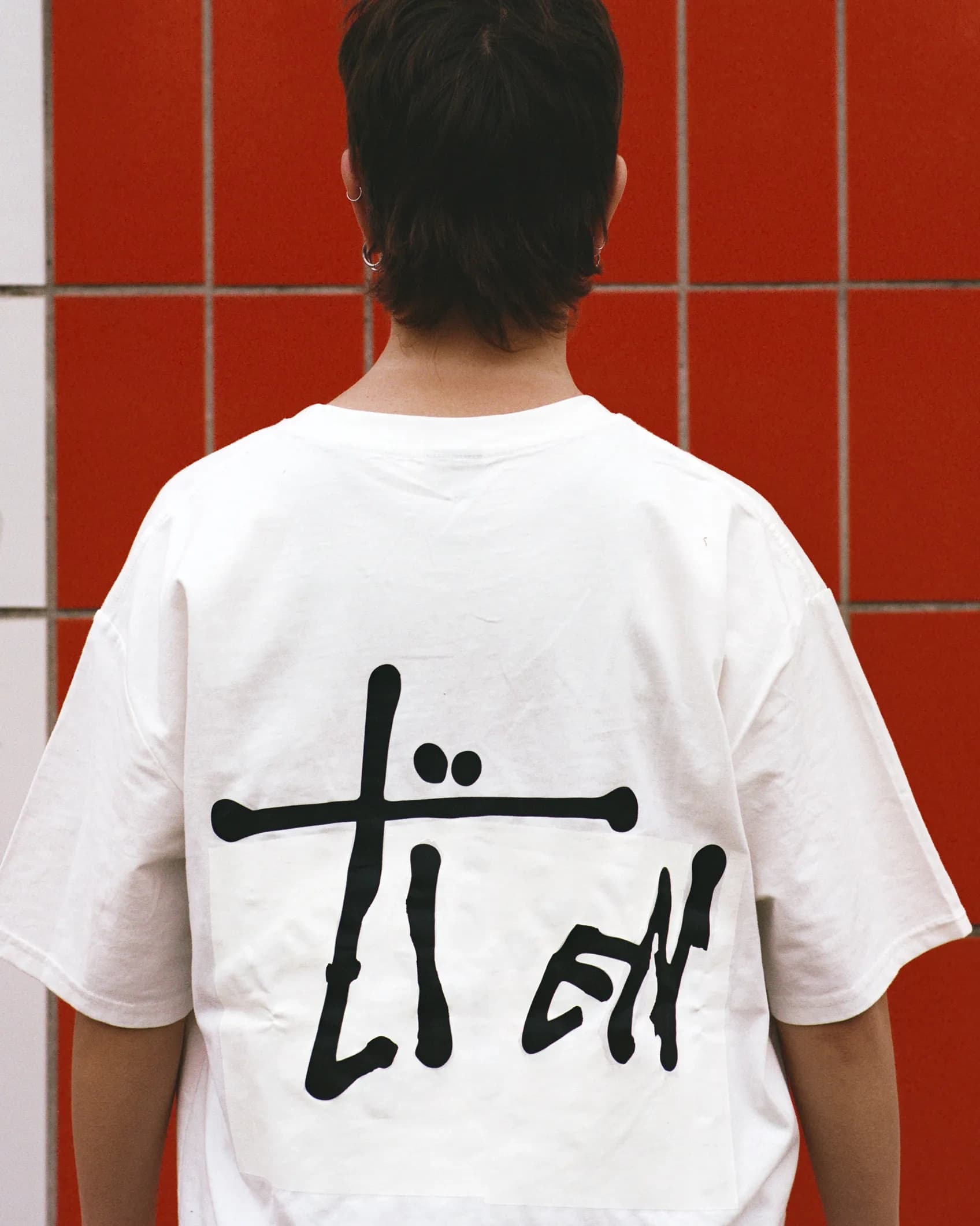 Back of a white Stüssy t-shirt with the signature script logo reworked to read TIEN, keeping the original handwritten letterform style intact.