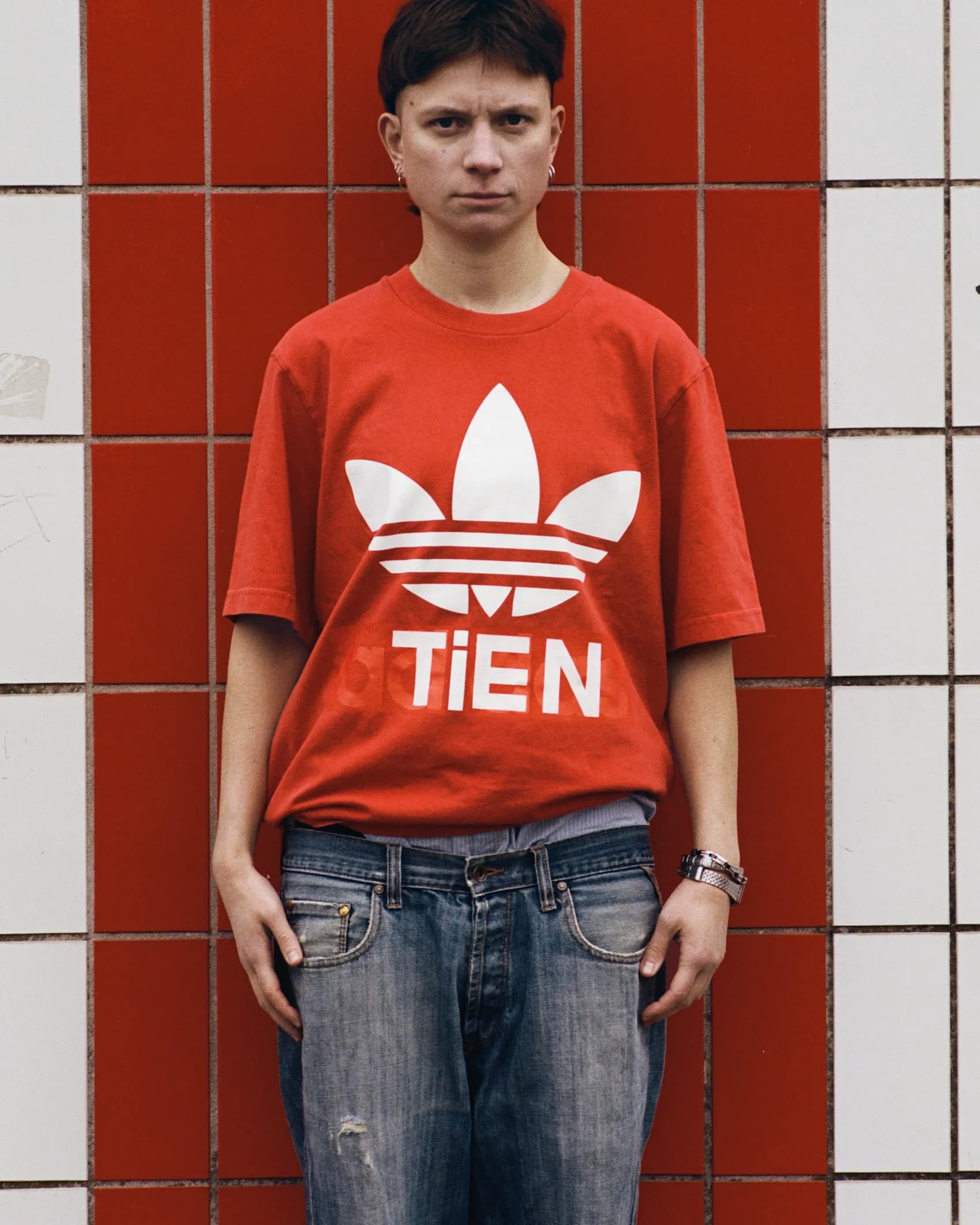 Close-up of a red Adidas Originals t-shirt with the brand name replaced by TIEN, keeping the trefoil logo and original typeface intact.