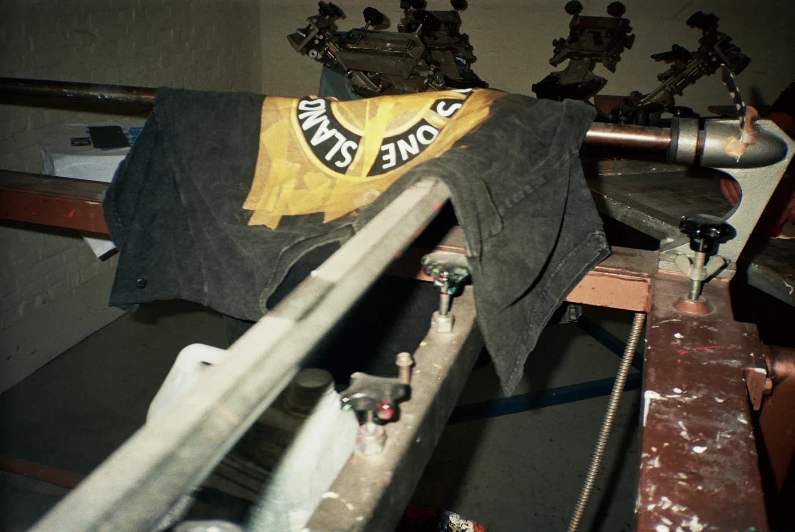 Behind the scenes shot of a vintage Stone Island t-shirt loaded onto a silkscreen press, mid-process of being reworked with the TIEN identity.